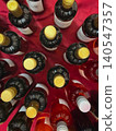 Wine bottles stand on red tablecloth top view, blurred caps, glass, labels, table display for tasting. Concept of wine tasting, catering service, beverage selection, reception event bar 140547357