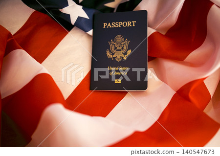 United States passport resting on folded American flag, showcasing the emblem and text clearly against the vibrant red, white, and blue colors of the flag United States passport resting on folded American flag, showcasing the emblem and text clearly against the vibrant red, white, and blue colors of the flag 140547673