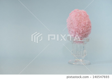 Pink cotton candy displayed in a clear glass dessert cup against a soft blue background, highlighting the fluffy texture and vibrant color of the treat Pink cotton candy displayed in a clear glass dessert cup against a soft blue background, highlighting the fluffy texture and vibrant color of the treat 140547693