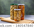 Preserving pickled forest mushrooms in glass jars on chopping board 140547840