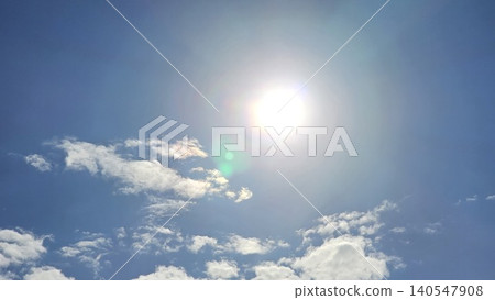 Bright sun shining in blue sky with white scattered clouds and lens flare effect on foreground, concept of hot summer weather and pure nature Bright sun shining in blue sky with white scattered clouds and lens flare effect on foreground, concept of hot summer weather and pure nature 140547908