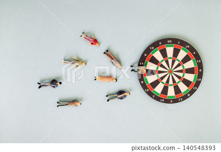 Miniature figurines scattered around a dartboard on a light blue background, depicting a playful scene of a dart game with various colorful figures Miniature figurines scattered around a dartboard on a light blue background, depicting a playful scene of a dart game with various colorful figures 140548393