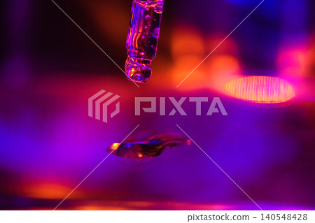 Close-up of a dropper releasing a droplet of liquid against a vibrant, colorful background with purple and orange hues creating a dynamic visual effect Close-up of a dropper releasing a droplet of liquid against a vibrant, colorful background with purple and orange hues creating a dynamic visual effect 140548428