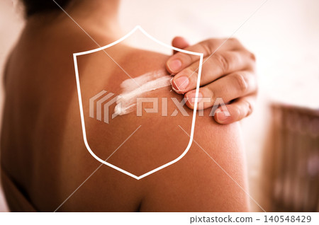 Woman applying sunscreen lotion on shoulder, showing tanned skin and white cream, with blurred background of a sunlit indoor setting and soft textures Woman applying sunscreen lotion on shoulder, showing tanned skin and white cream, with blurred background of a sunlit indoor setting and soft textures 140548429