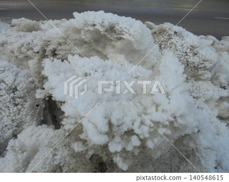 Mounded snow boulders covered by dense white frost next to the road. 140548615