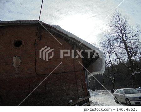 Brick building with horse head statue and snow sliding down from the roof. Brick building with horse head statue and snow sliding down from the roof. 140548623