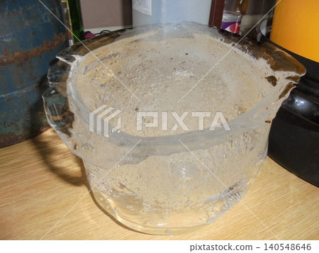 Bucket-shaped piece of ice with bubbles of air inside standing on a ktichen unit Bucket-shaped piece of ice with bubbles of air inside standing on a ktichen unit 140548646