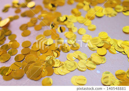 Close-up view of scattered golden confetti circles on a light surface, reflecting light and creating a festive atmosphere suitable for celebrations and events Close-up view of scattered golden confetti circles on a light surface, reflecting light and creating a festive atmosphere suitable for celebrations and events 140548881