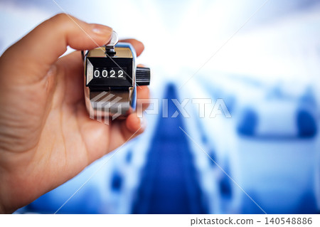 Hand holding a mechanical tally counter displaying the number 22 against a blurred background of a modern indoor space with soft lighting Hand holding a mechanical tally counter displaying the number 22 against a blurred background of a modern indoor space with soft lighting 140548886