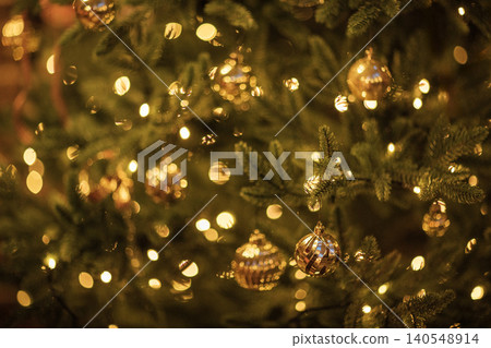 Christmas tree adorned with golden ornaments and warm fairy lights, creating a festive atmosphere with blurred background bokeh effect for holiday decoration 140548914