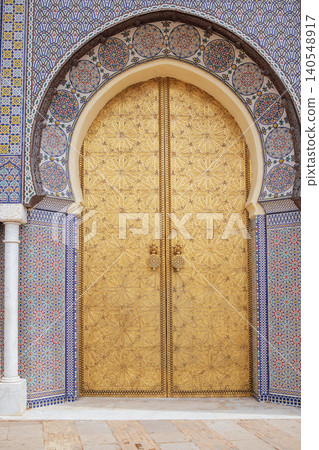Ornate golden doors with intricate patterns and decorative tiles, framed by an archway, showcasing stunning craftsmanship and cultural heritage in architectural design 140548917