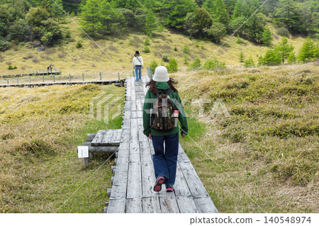 Hikers walking along the boardwalk in Ikenotaira Marshland, Tomi City, Nagano Prefecture Hikers walking along the boardwalk in Ikenotaira Marshland, Tomi City, Nagano Prefecture 140548974