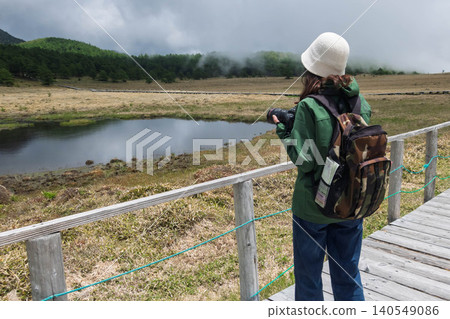 A woman photographs Kagami Pond in Ikenotaira Marshland, Tomi City, Nagano Prefecture. A woman photographs Kagami Pond in Ikenotaira Marshland, Tomi City, Nagano Prefecture. 140549086