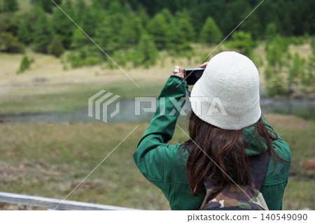 A woman photographs Kagami Pond in Ikenotaira Marshland, Tomi City, Nagano Prefecture. A woman photographs Kagami Pond in Ikenotaira Marshland, Tomi City, Nagano Prefecture. 140549090