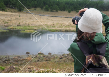 A woman photographs Kagami Pond in Ikenotaira Marshland, Tomi City, Nagano Prefecture. A woman photographs Kagami Pond in Ikenotaira Marshland, Tomi City, Nagano Prefecture. 140549093