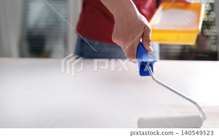 Girl Painting Wooden Board With White Paint Using Roller Girl Painting Wooden Board With White Paint Using Roller 140549523