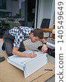Man measures furniture panel with ruler and pencil during DIY assembly 140549649