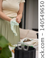Person puts on gardening gloves for plant care near pots, tools and clay pebbles 140549650
