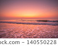 Serene ocean waves at sunrise with a distant fishing boat and crescent moon 140550228