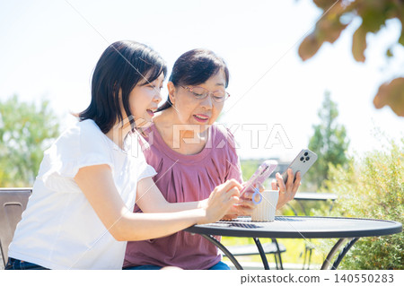Seniors and middle-aged women relaxing at an open-air cafe. Seniors and middle-aged women relaxing at an open-air cafe. 140550283