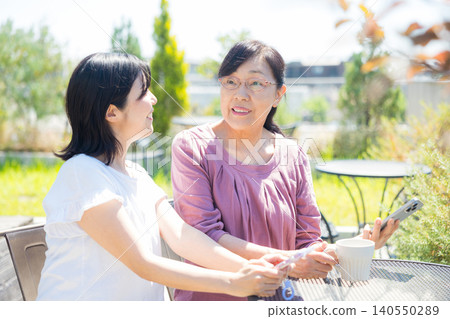 Seniors and middle-aged women relaxing at an open-air cafe. Seniors and middle-aged women relaxing at an open-air cafe. 140550289