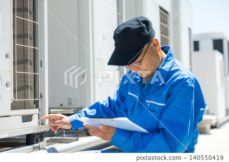 Senior citizen inspecting outdoor air conditioning units on the rooftop of an office building. Senior citizen inspecting outdoor air conditioning units on the rooftop of an office building. 140550419