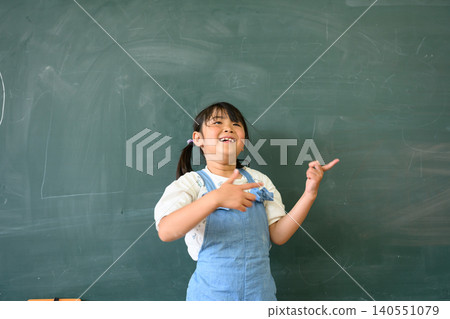 一名小學生面帶微笑,指著教室黑板前。 一名小學生面帶微笑,指著教室黑板前。 140551079