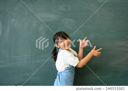 一名小學生面帶微笑,指著教室黑板前。 一名小學生面帶微笑,指著教室黑板前。 140551081