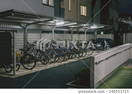 Bicycles lined up in a bicycle parking area at an apartment complex at night Bicycles lined up in a bicycle parking area at an apartment complex at night 140551725