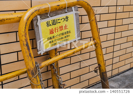 A yellow barricade and warning sign indicate that the road is private and therefore off-limits to traffic. A yellow barricade and warning sign indicate that the road is private and therefore off-limits to traffic. 140551726