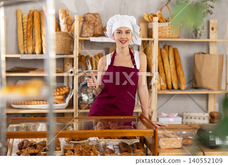 Young woman seller at counter in bakery Young woman seller at counter in bakery 140552109