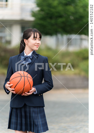 High school, junior high school, and elementary school girls in uniform standing in a schoolyard holding a basketball High school, junior high school, and elementary school girls in uniform standing in a schoolyard holding a basketball 140552182