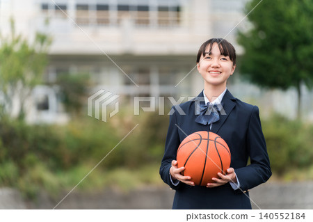 High school, junior high school, and elementary school girls in uniform standing in a schoolyard holding a basketball High school, junior high school, and elementary school girls in uniform standing in a schoolyard holding a basketball 140552184