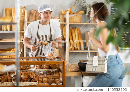 Young man seller gives customer order, guy serves customers girl in bakery. 140552303