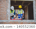 Construction workers using level tool to check window frame alignment during building inspection 140552360