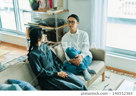 A young Japanese couple chatting with smiles on their faces. 140552365