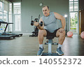 Senior Man Lifting Dumbbell on Bench in Gym 140552372