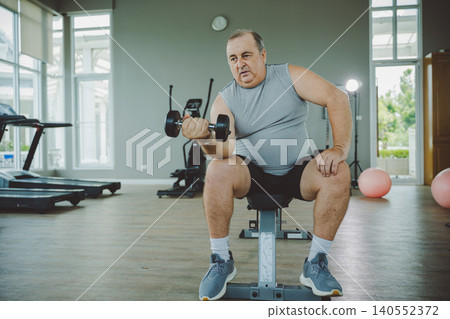 Senior Man Lifting Dumbbell on Bench in Gym Senior Man Lifting Dumbbell on Bench in Gym 140552372