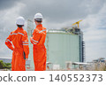 Oil and gas engineers surveying LNG tank site with digital tablet and communication tools 140552373