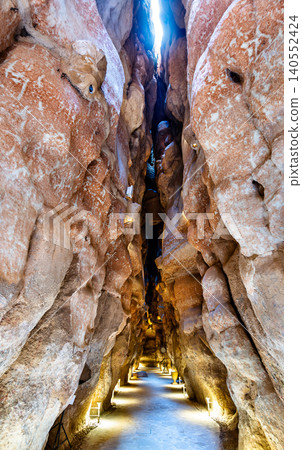 Illuminated narrow passage inside the ancient Al Qarah Mountain caves in Al Ahsa, Saudi Arabia, a popular natural tourist attraction. Illuminated narrow passage inside the ancient Al Qarah Mountain caves in Al Ahsa, Saudi Arabia, a popular natural tourist attraction. 140552424