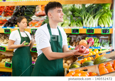 Male shopping assistant helping customer to buy pomegranate fruit in shop 140552472