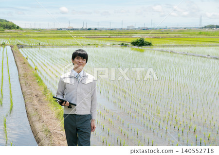 A man in work clothes looking at a rice field. A man in work clothes looking at a rice field. 140552718
