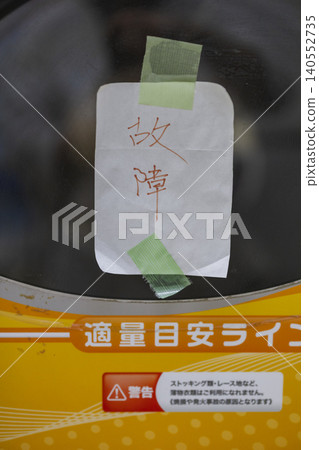 洗衣店裡的一台洗衣機,上面貼著一張手寫的「故障」告示。 洗衣店裡的一台洗衣機,上面貼著一張手寫的「故障」告示。 140552735