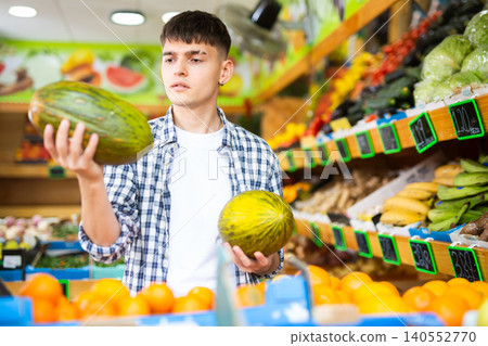 Young male consumer picking melon in hypermarket Young male consumer picking melon in hypermarket 140552770