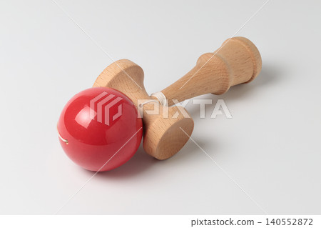 A wooden kendama placed horizontally against a white background. A wooden kendama placed horizontally against a white background. 140552872