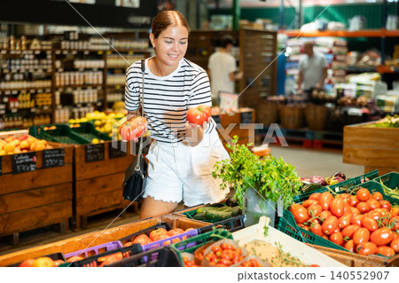 Young woman choosing tomatoes in grocery store Young woman choosing tomatoes in grocery store 140552907