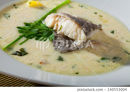 Tasty creamy soup with white fish hake and greens at plate Tasty creamy soup with white fish hake and greens at plate 140553004