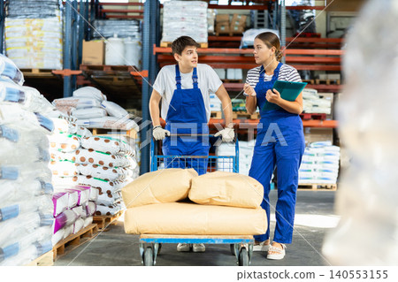 Girl check papers invoices together with guy employee and revise availability of goods in stock Girl check papers invoices together with guy employee and revise availability of goods in stock 140553155