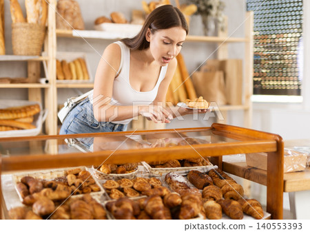 Young female buyer choosing croissants in bakery Young female buyer choosing croissants in bakery 140553393