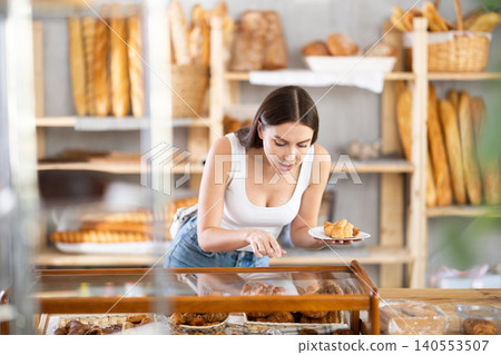 Young woman buyer chooses pastries in bakery Young woman buyer chooses pastries in bakery 140553507